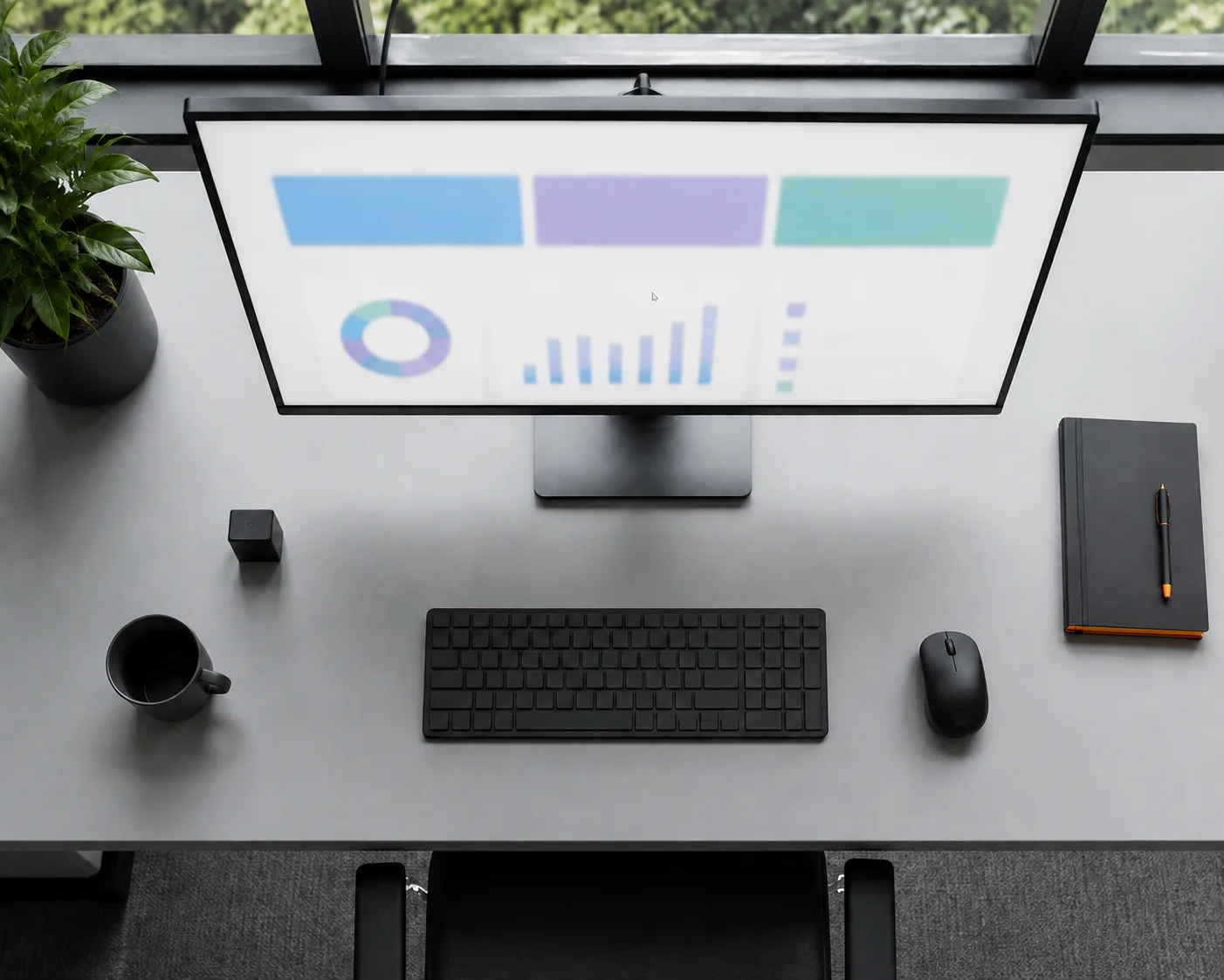 Schreibtisch von oben mit Monitor, der farbige Balken sowie ein Kreis- und ein Balkendiagramm zeigt, davor Tastatur, Maus, Notizbuch mit Stift, Kaffeetasse und eine Grünpflanze.